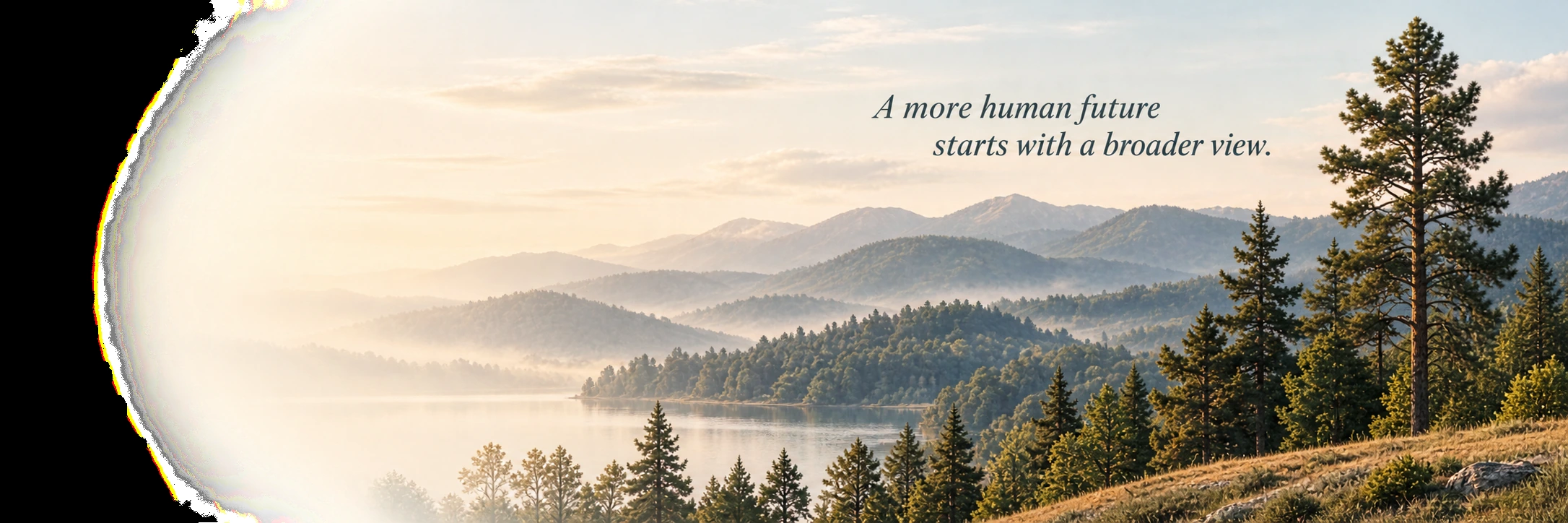 A misty lake at dawn below layered blue ridges, with pines along the near shore and a tall pine at the right.